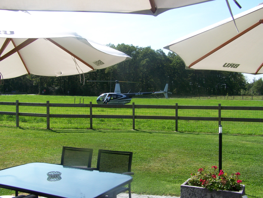 Hélicoptère posé dans le jardin d'un restaurant, vu depuis la terrasse
