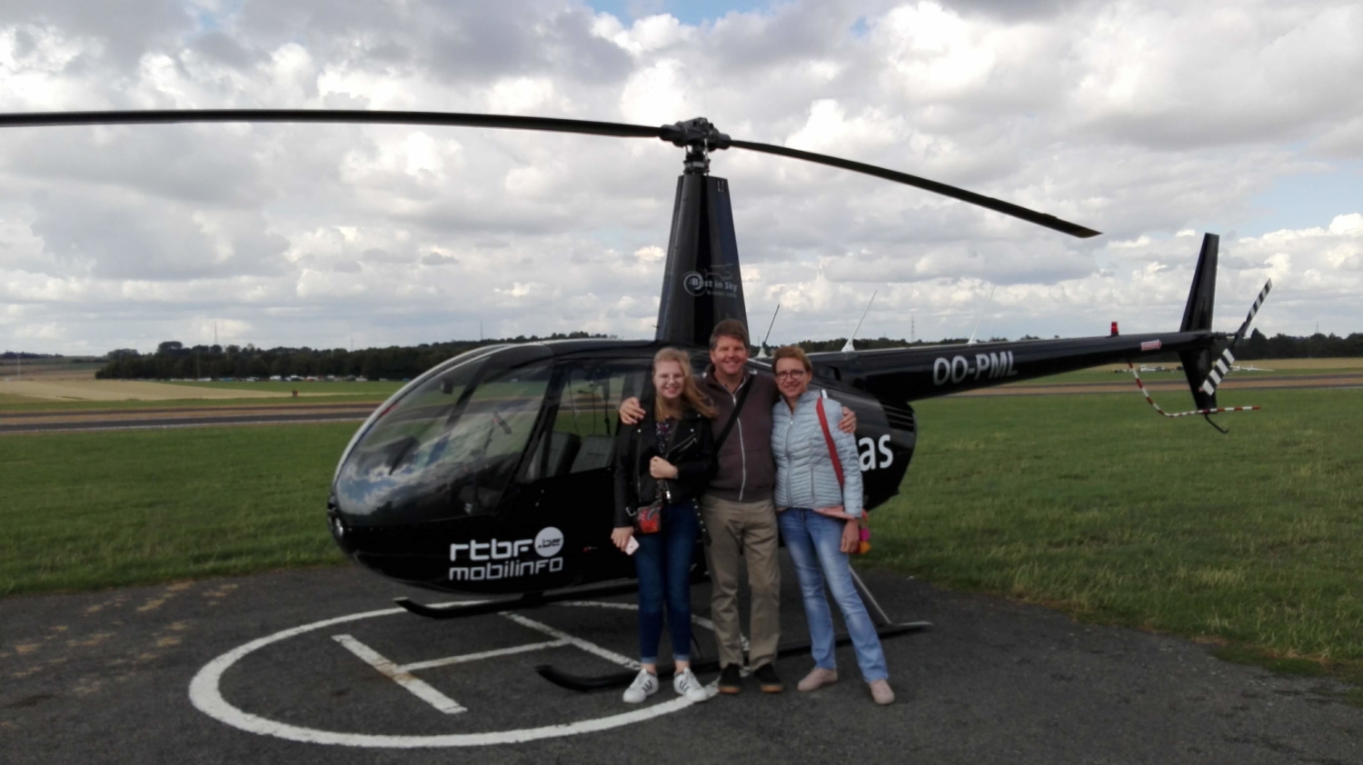 Famille souriante devant le Robinson R44 après une balade