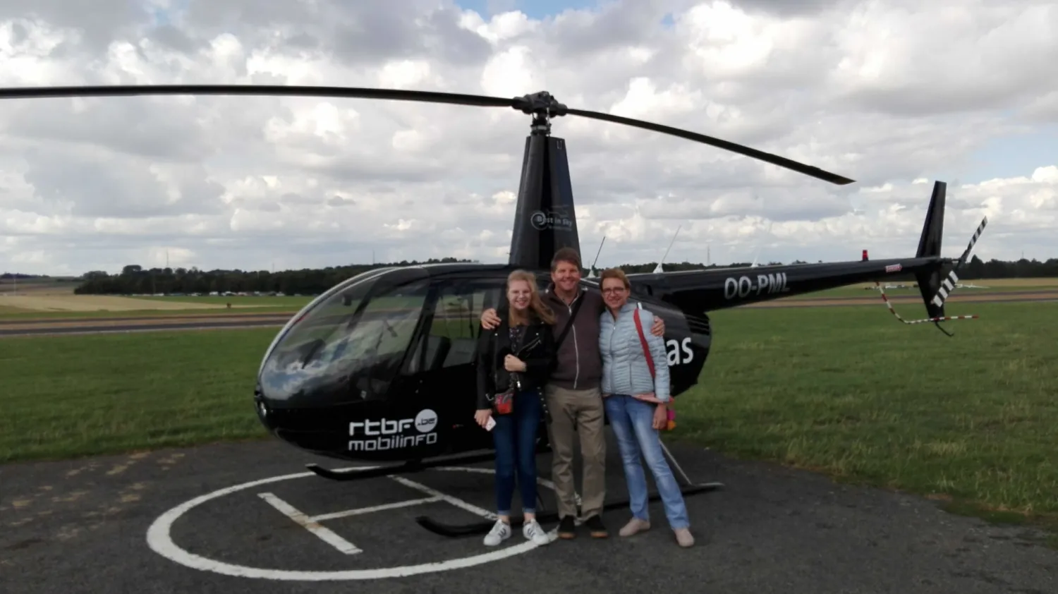 Famille souriante devant le Robinson R44 après une balade